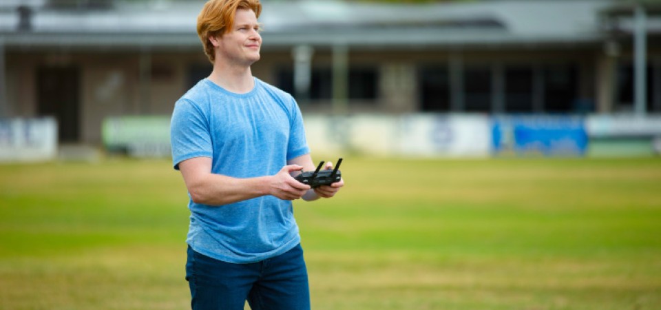 A man flying a drone in a field