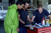 A group of engineers reviewing documents on top of a toolbox in a hangar
