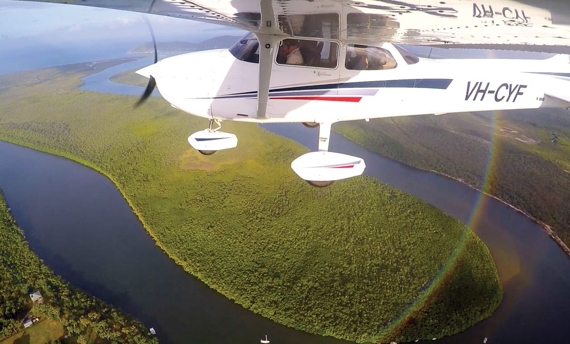 A Cessna 172S flying over a river in Queensland