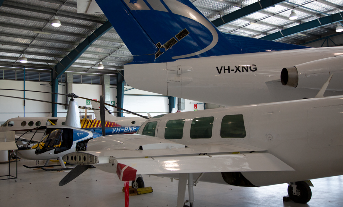 Fokker F28 (VH-XNG) and Robinson R44 (VH-BNE) and in an Aviation Australia hangar at Brisbane Airport in February 2013