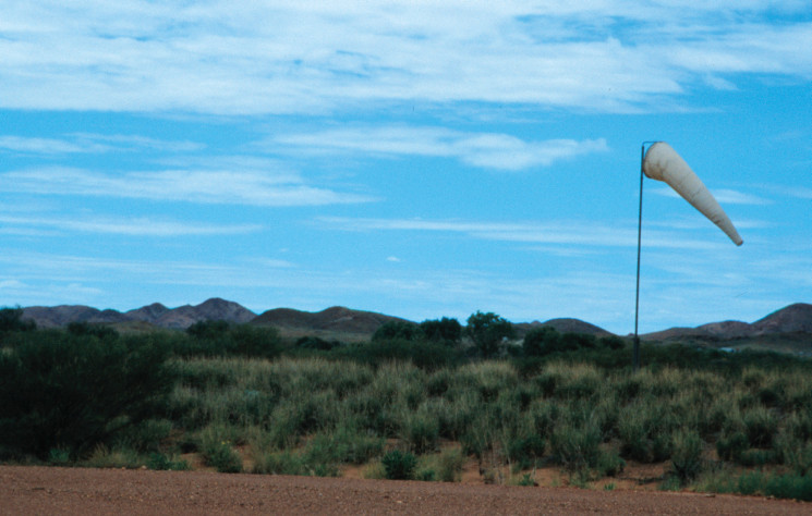 A windsock on a scrubby outback field, highlighted against the sky