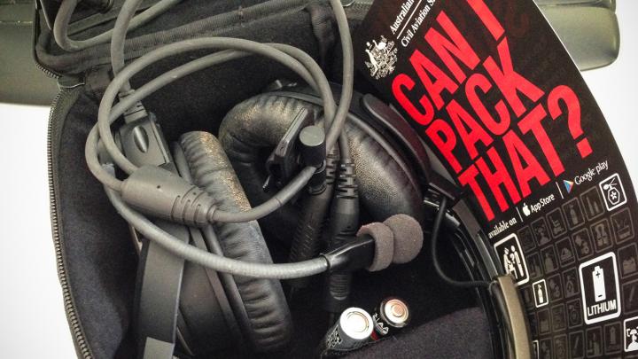 Headphones in a case with Can I pack that? reference card