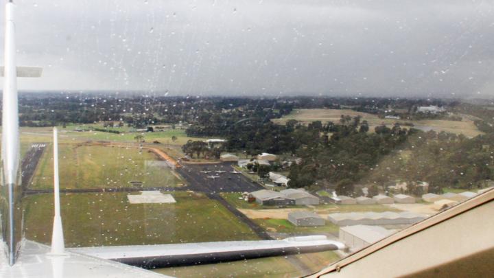 View outside aircraft window showing clouds and rain