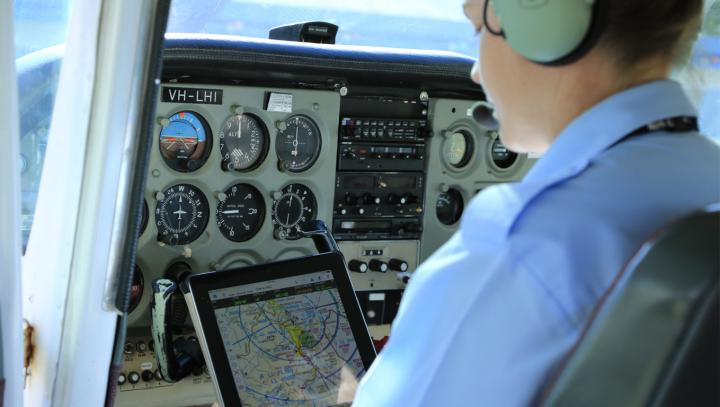 Pilot using a tablet in a coockpit of a stationary aircraft
