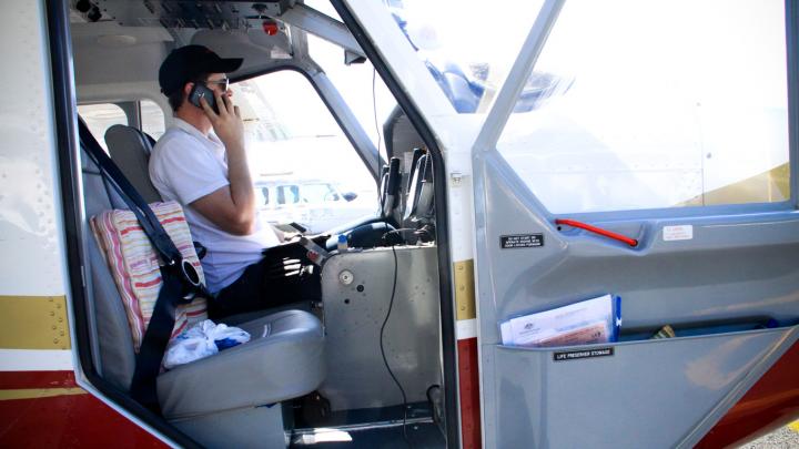 Pilot sitting in stationary aircraft on mobile phone