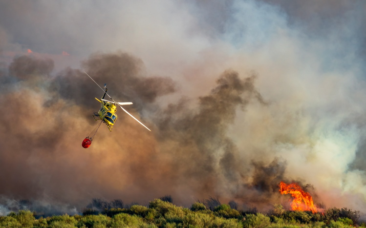 Helicopter flying with water bombing over bushfire