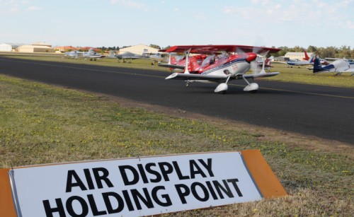 A small plane on runway taking off, with a sign labelled "Air display holding point" in the foreground