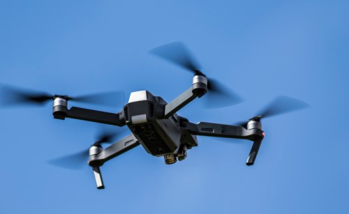A quadcopter drone flying in a cloudless blue sky