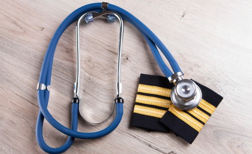 A stethoscope lies atop a pair of pilot's epaulettes on a table
