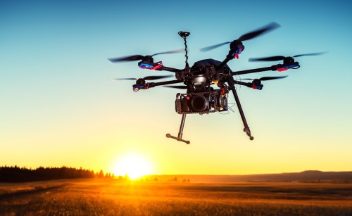 A multirotor drone silhouetted against the darkening sky of a sunset