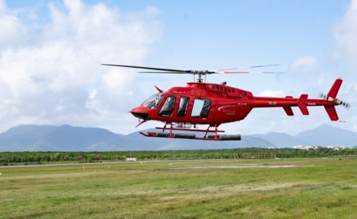 A red helicopter landing in a field