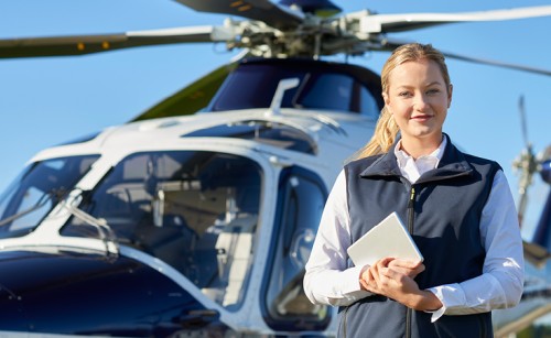 A female pilot standing in front of a helicopter
