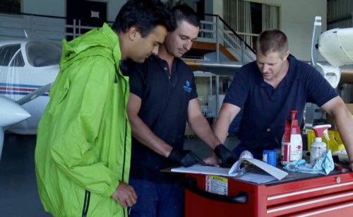 A group of engineers reviewing documents on top of a toolbox in a hangar
