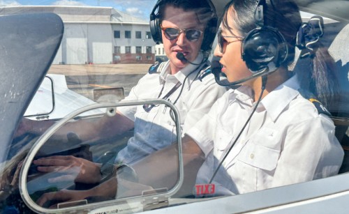 A male and female pilot talking to each other in the cockpit of an aeroplane