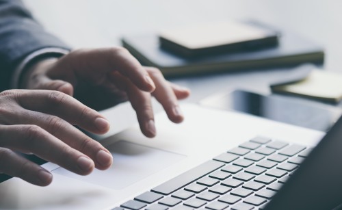 A person's hands typing on the keyboard of a laptop