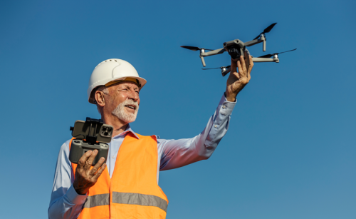 A man in a high visibility vest and a hard hat holding a drone