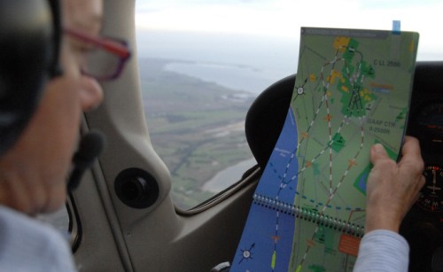 A pilot examines a map while flying