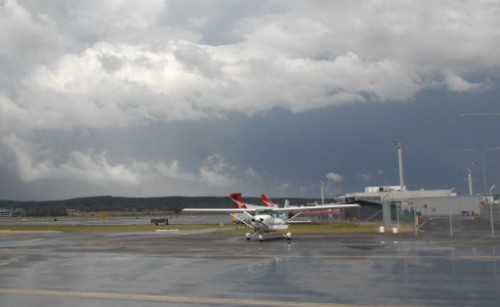 An aeroplane is parked on the apron of an airport on a cloudy day