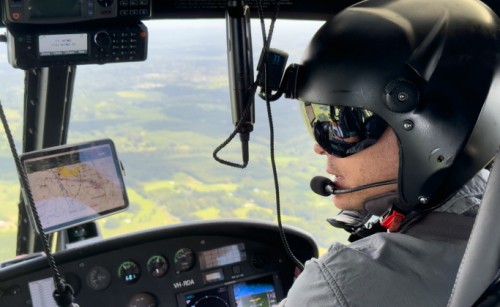 A pilot wearing a helmet flying over the countryside