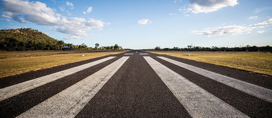 A runway running towards the horizon, with its stripes covering much of the foreground.