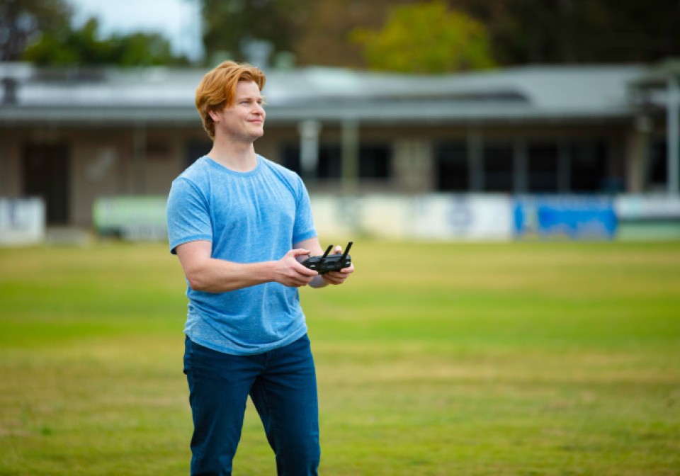 A man flying a drone in a field