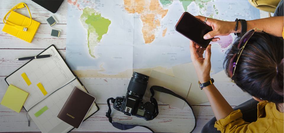 Someone on their phone with a map laid out on the table in front of them.
