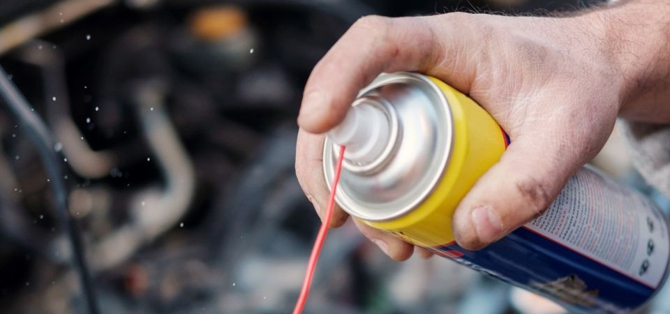 A hand holding an aerosol spray can of degreaser