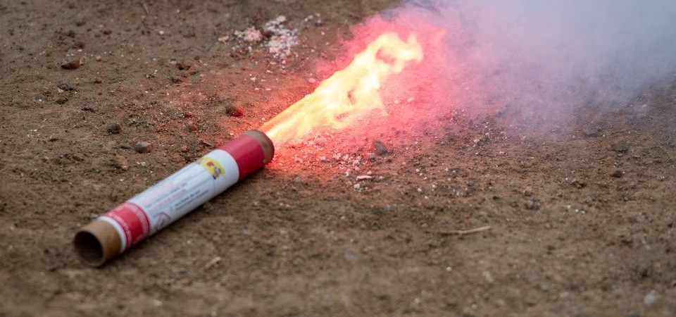 A burning signal flare lying on the ground