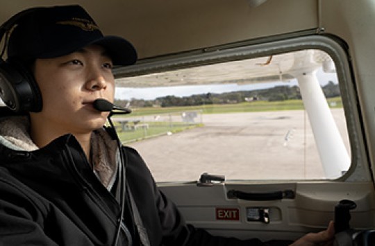 A pilot in his plane with a radio headset on