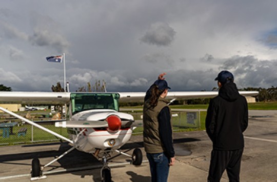 Two pilots standing outside a plane evaluating the weather