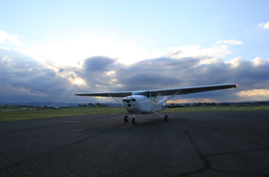 To the left, logos and title text "Australian government - Civil Aviation Safety Authority" "AvSafety - Awareness through education" "Webinar: Weather and Forecasting" To the right, a diagonal blue slash dividing the image into two sections, then a picture of a red-and-white plane sitting on a runway, with dark clouds in the sky behind it.