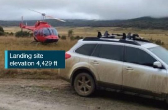 A car on a road with a red helicopter crashed into a field behind it. Text: "Landing site elevation 4,429 ft"