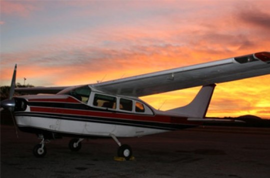 A plane sits on the ground as the sun rises behind it