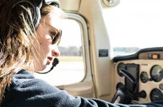 A female pilot setting the radio of a small airplane