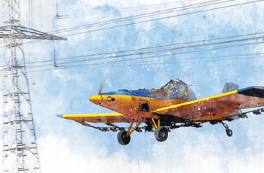 A yellow and blue plane with power transmission lines in the foreground