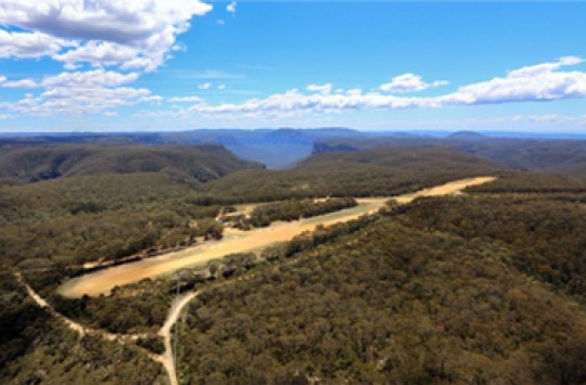 An aerial view of a dirt runway in the middle of the bush