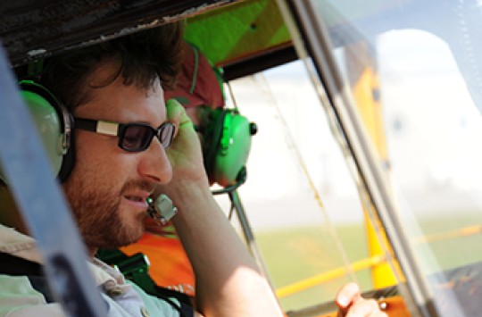 A pilot in the cockpit of a plane talking on his radio headset