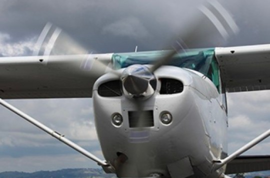 An aeroplane on the ground spinning up its propeller even though the sky is covered in clouds