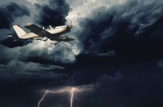 Small plane flying with a lightning strike in the background