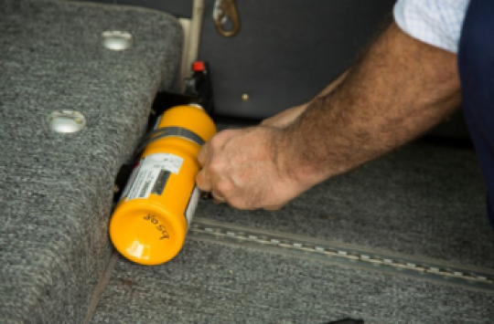 A man securing a fire extinguisher to the floor of an aircraft