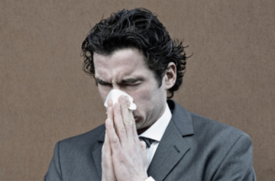 A man in a suit blowing his nose
