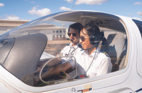 A male and female pilot sitting in the cockpit of an aeroplane