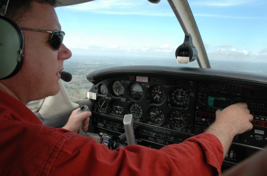 A pilot flying an aeroplane, conducting checks on his cockpit avionics