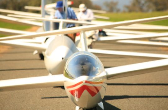 A series of gliders lined up in a row at an airport