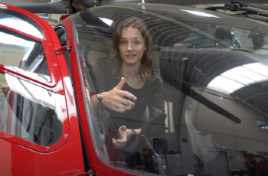 Person in cockpit of parked helicopter