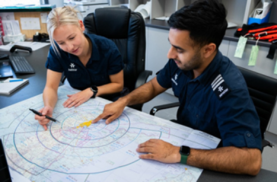2 pilots at a desk looking at maps
