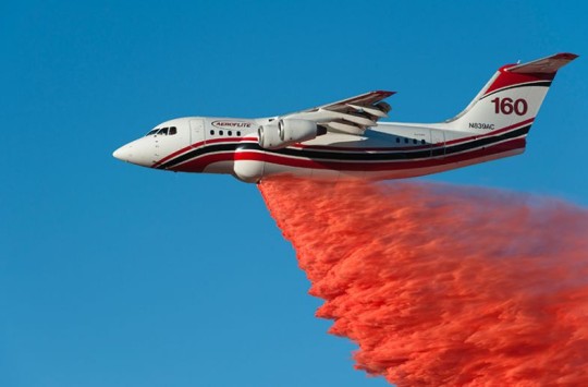 A firefighting aeroplane dropping red fire retardant