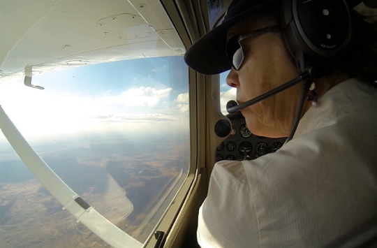 A pilot looking out the side window of their cockpit