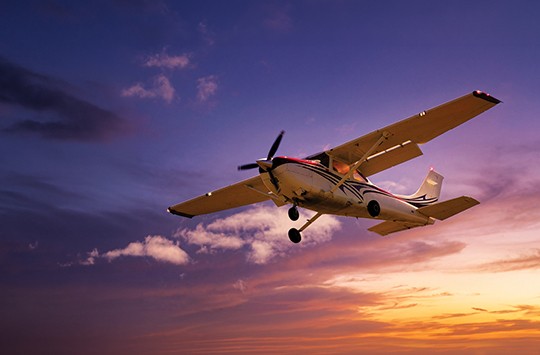 An aeroplane flying with the sun setting behind it
