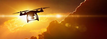 A drone silhouetted against the golden rays of the sun, with a dark cloud below it